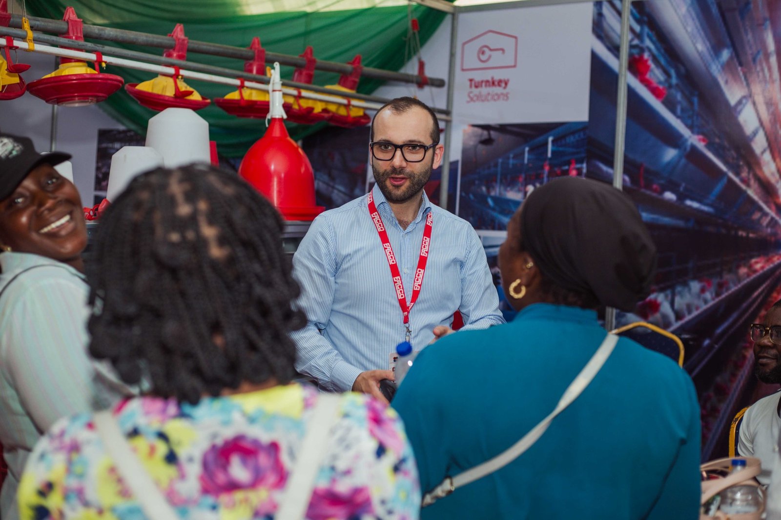 An exhibitor discussing poultry equipment with visitors.